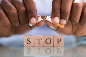 hands breaking a cigarette over blocks spelling the word stop