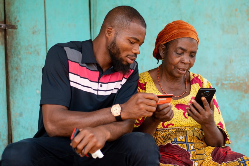 Man and woman view a mobile device to complete a mobile money transaction.