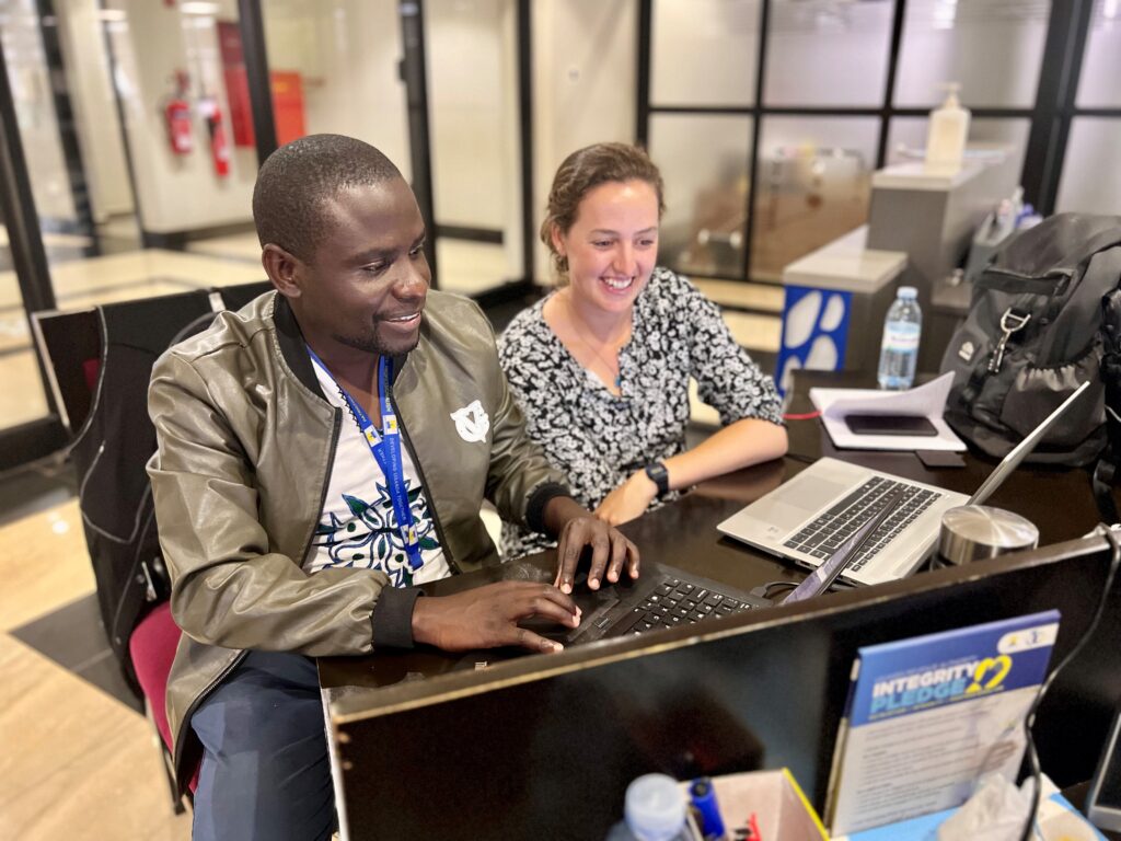 an ICTD researcher working at a laptop with an official from the Uganda Revenue Authority