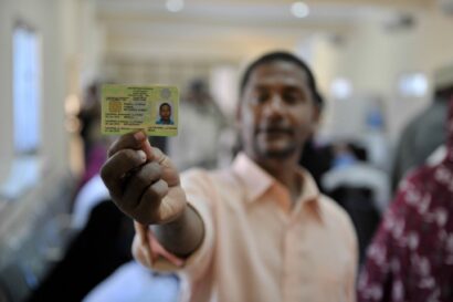 blurred man holding his ID in focus to the camera.