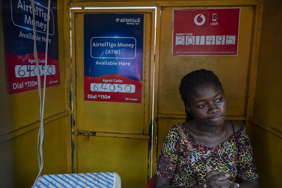 Esta Sechbeia (24) looks on as she waits for customers at a mobile money stand on the side of the road in the Tesano neighbourhood, Ghana.