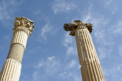two ancient Greek columns that are cracked , against a blue sky