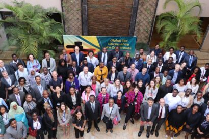 group of about 100 people standing in front of the conference banner in the courtyard of the venue