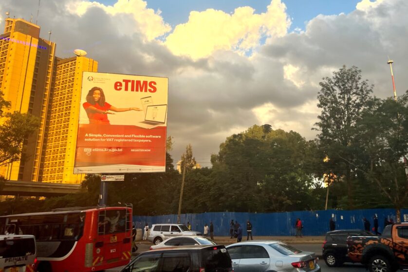 Nairobi skyline at sunset with a billboard that says eTims and features a woman in a red dress.