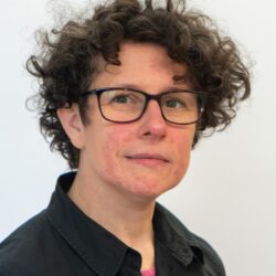 A portrait a Caucasian woman with short curly hair and glasses.