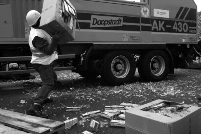 Man in protective gear throwing a box full of smuggled Malboro cigarettes in a shredding truck to destroy them.