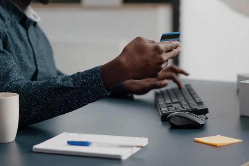 Close up of african american man hands typing credit card info on computer keyboard, online internet shopping leisure activity time. Business payment with web technology. Buying purchase transactions