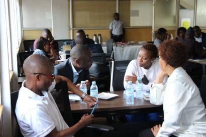 Two men and two women seated across a table in a group discussion.