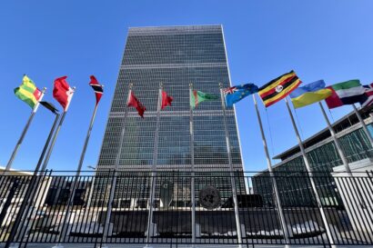 A photo of the UN Headquarters in New York with flags of several countries flying high.