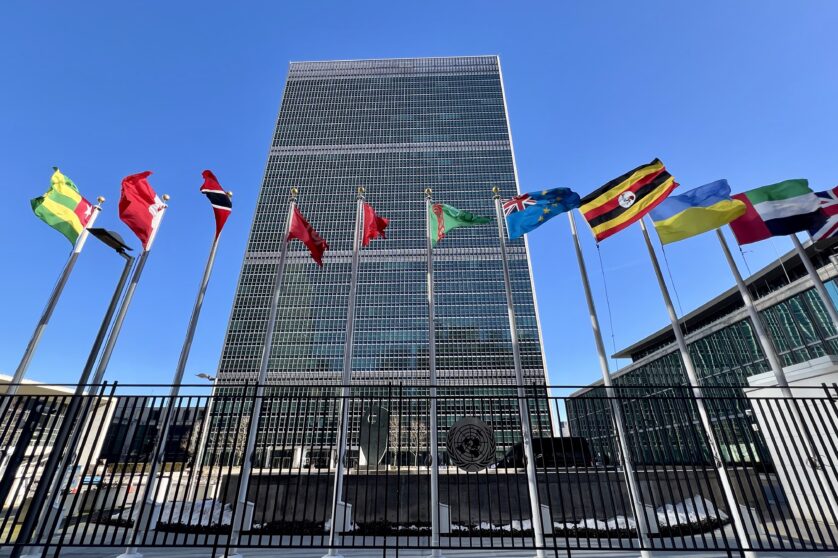 A photo of the UN Headquarters in New York with flags of several countries flying high.