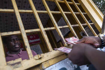 A customer counts cash before having funds transferred to his phone at a mobile money exchange.