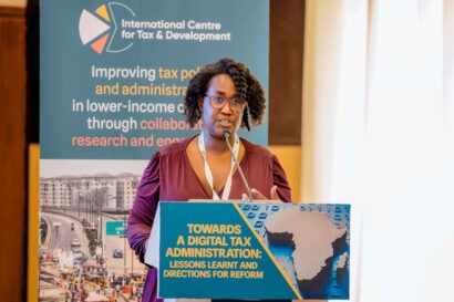Daisy Ogembo standing behind a lectern giving a presentation