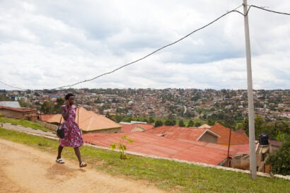 A woman walking along the streets of Kigali, talking on the phone.