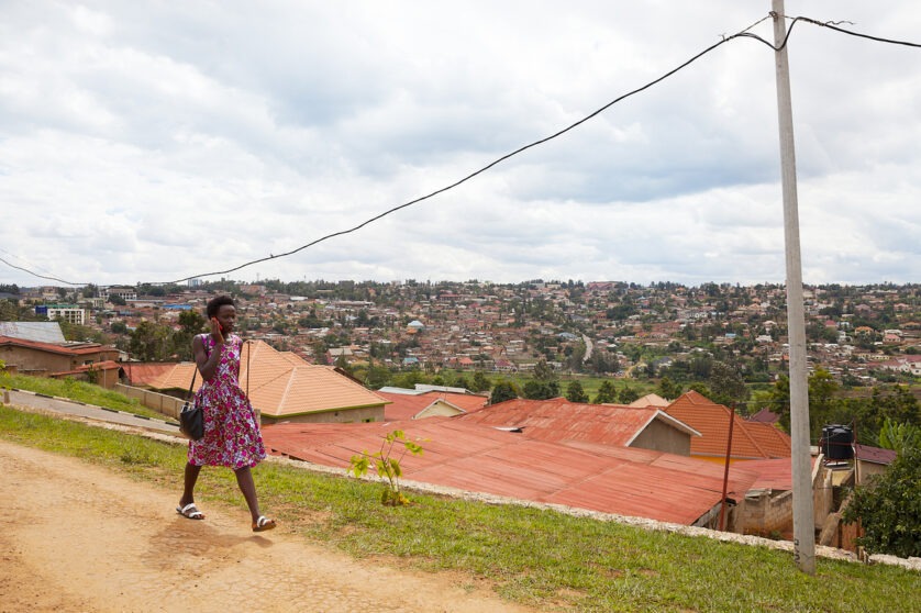 A woman walking along the streets of Kigali, talking on the phone.