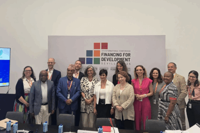 Group photo showing around 15 people smiling at the camera in front of a banner that reads "Financing for Development".
