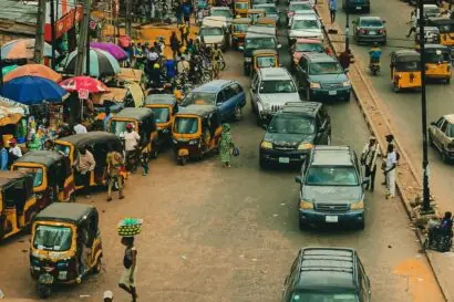 High angle shot of a wide busy market street in Nigeria filled with cars.