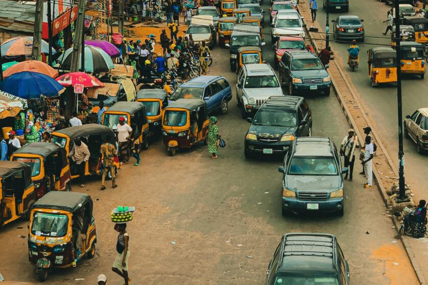 High angle shot of a wide busy market street in Nigeria filled with cars.