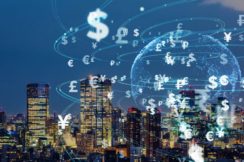 A city landscape superimposed by a transluscent globe with currency symbols around it.