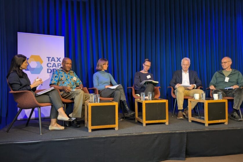 A panel of five speakers on a stage, having a discussion