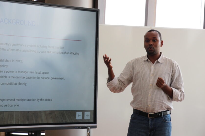Najibullah Nor Isak, ICTD tax course alum, standing in front of a projected screen as he delivers a presentation to an audience that is not seen in the picture.