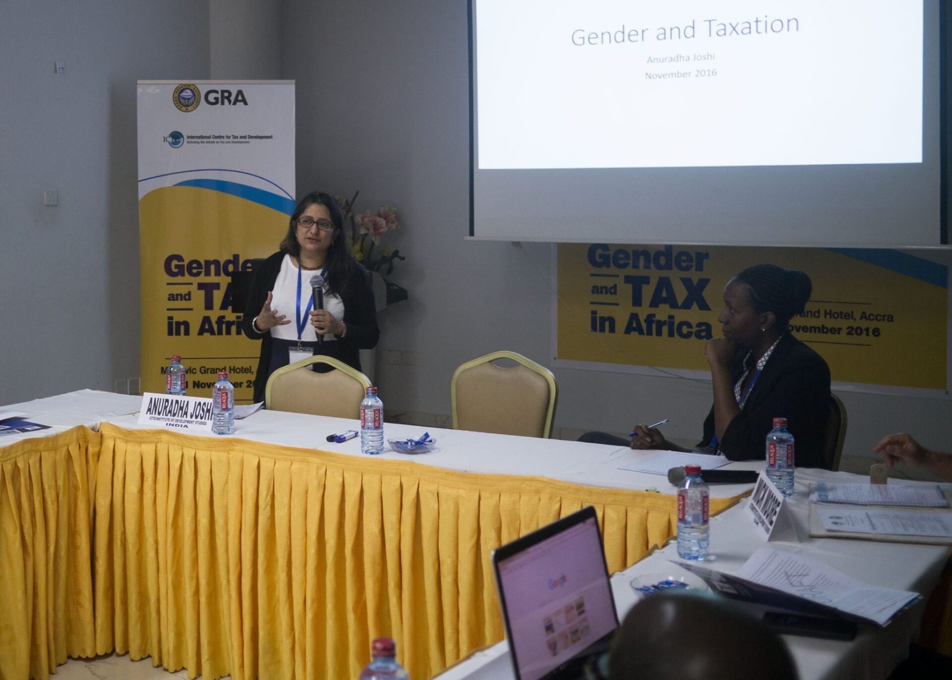 Joshi stands in front of a conference room to give a presentation.