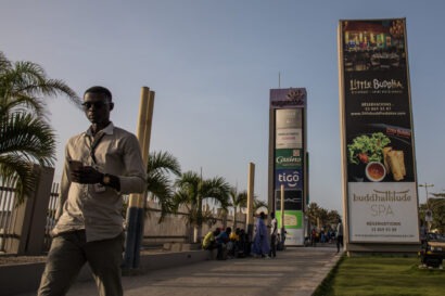 In Senegal a man is walking on the street as he checks his phone passing by Sea Plaza, the biggest mall in Dakar.