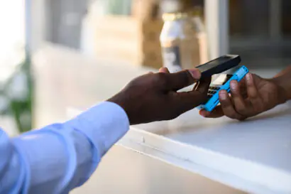 Customer making a contactless mobile payment using a smartphone and handheld card reader.