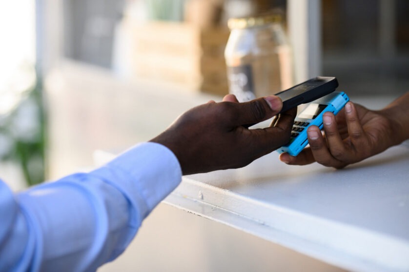 Customer making a contactless mobile payment using a smartphone and handheld card reader.