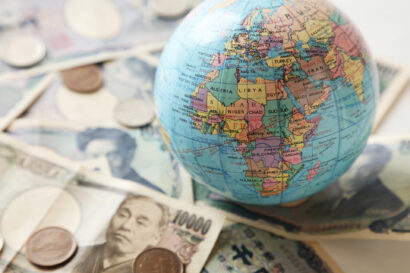 Globe showing the African continent on top of a pile of international currencies.