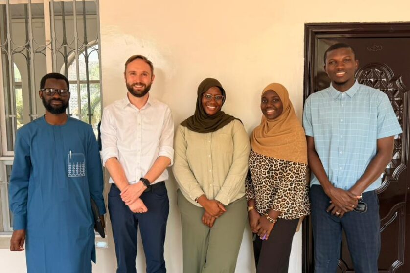 Five individuals standing side-by-side each other, smiling at the camera.